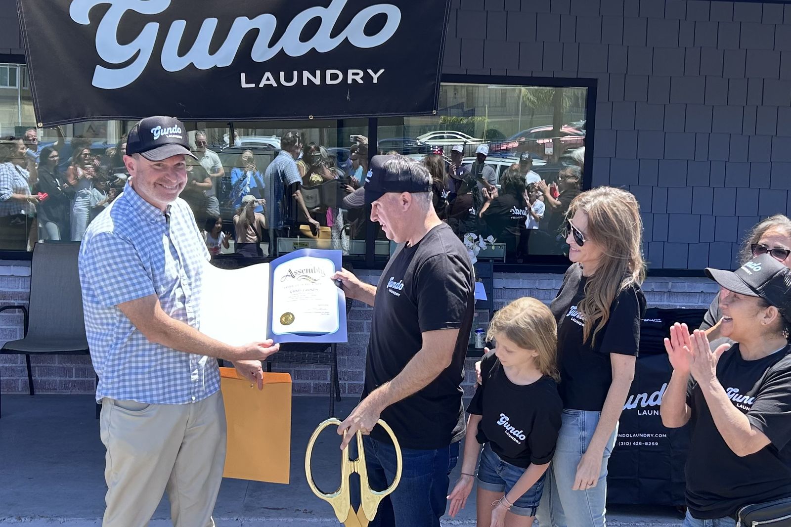 Ryan Baldino presenting a framed certificate outside the Gundo Laundry Company on its opening day.