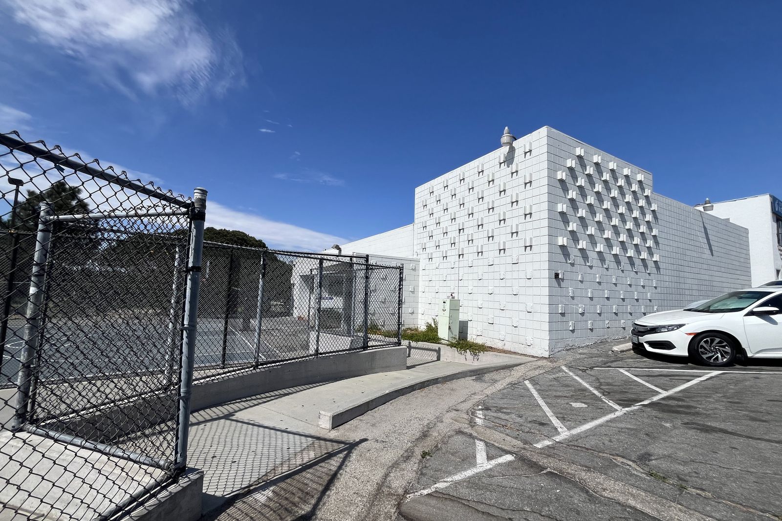 The exterior of the El Segundo teen center, a white perforated block facade under a clear sky.